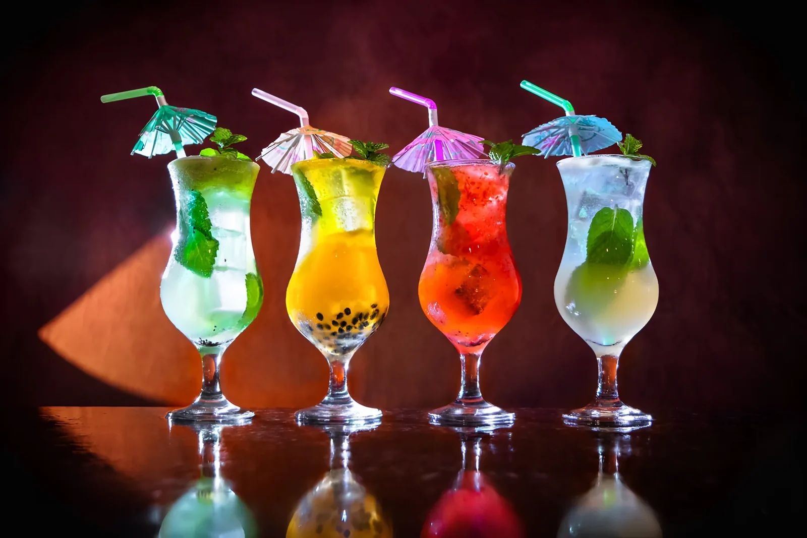 Quatro drinks coloridos servidos em taças